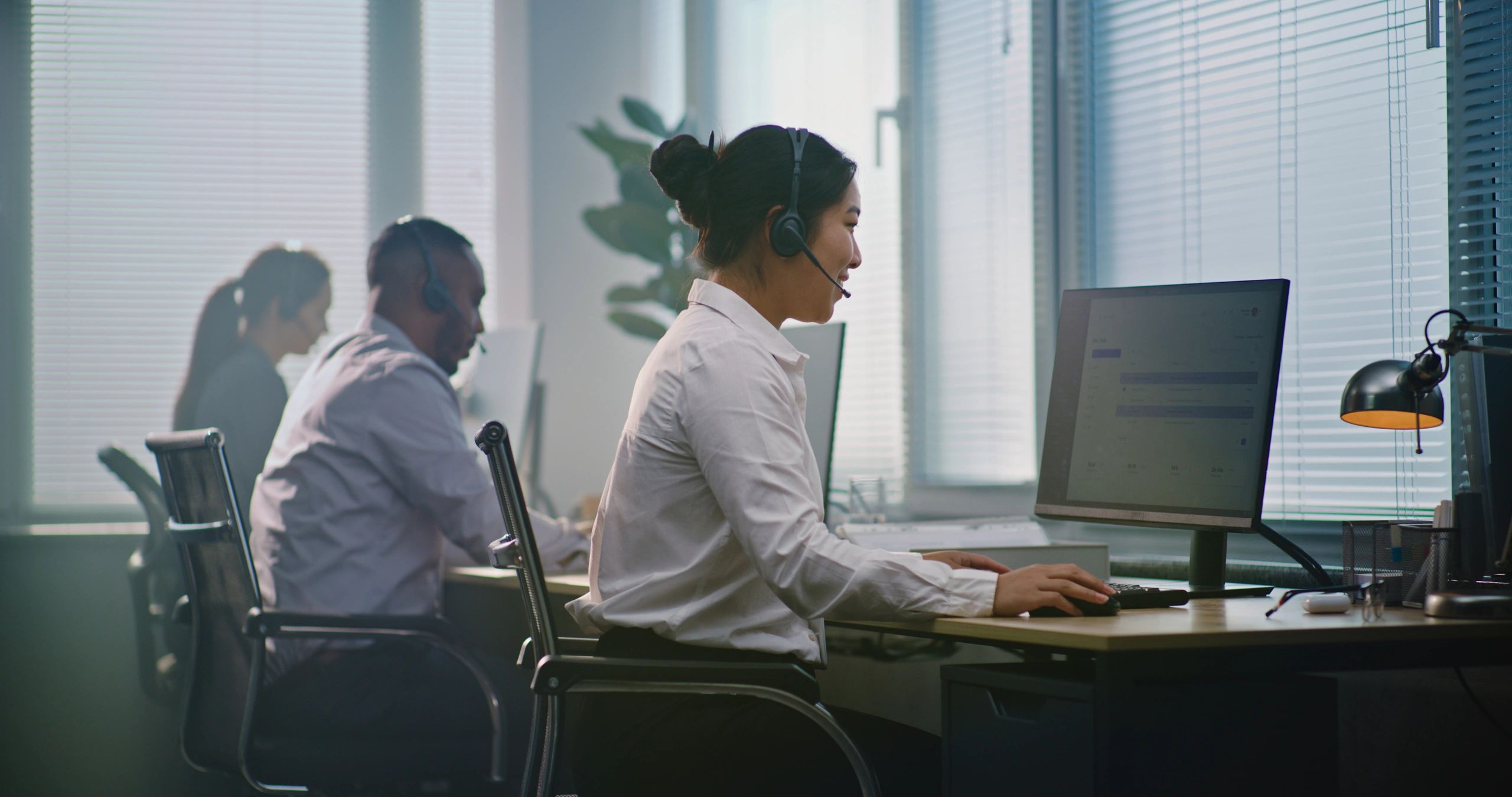 Helpdesk specialist assisting customers with a headset and computer