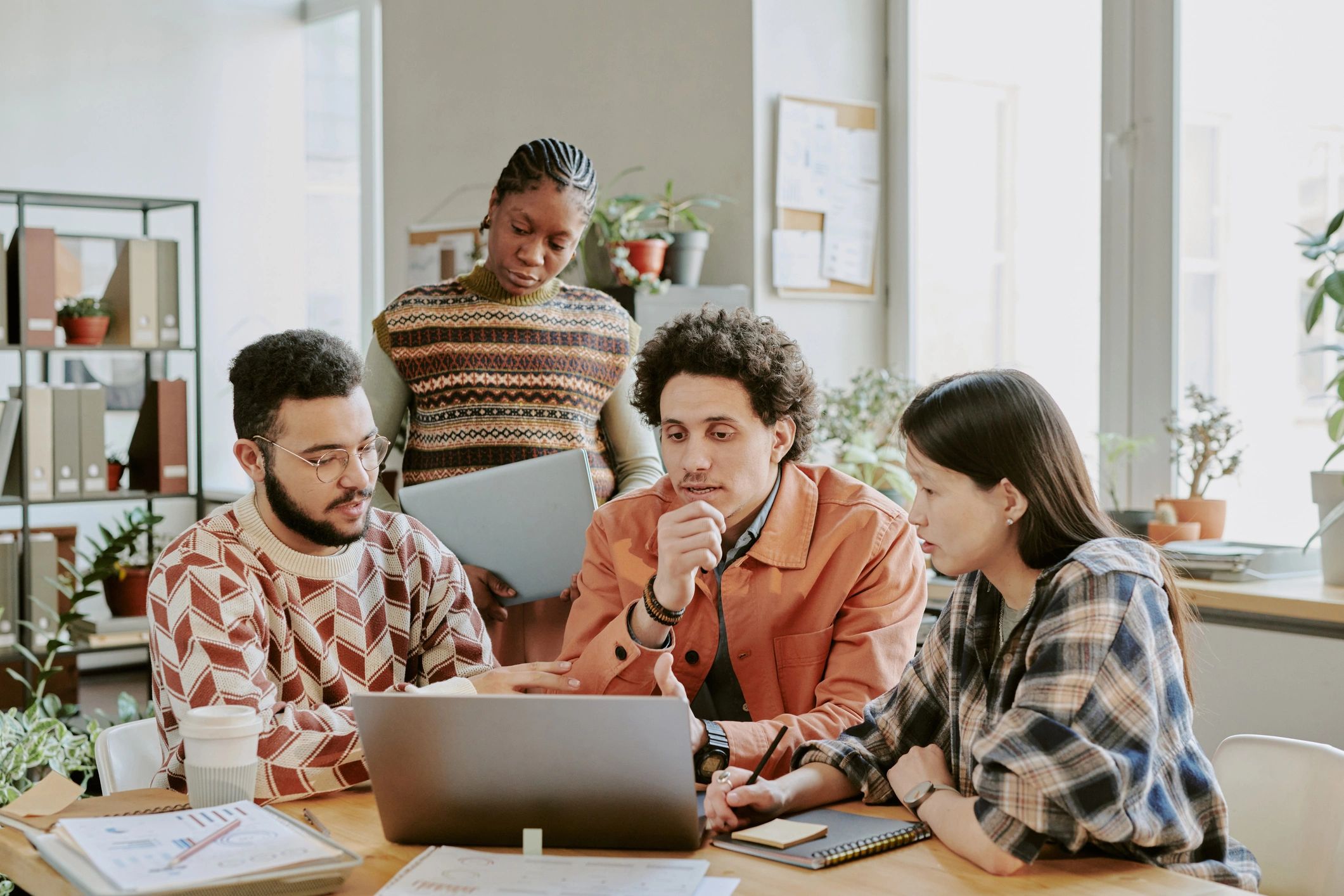 Developers collaborating around a laptop during a project meeting